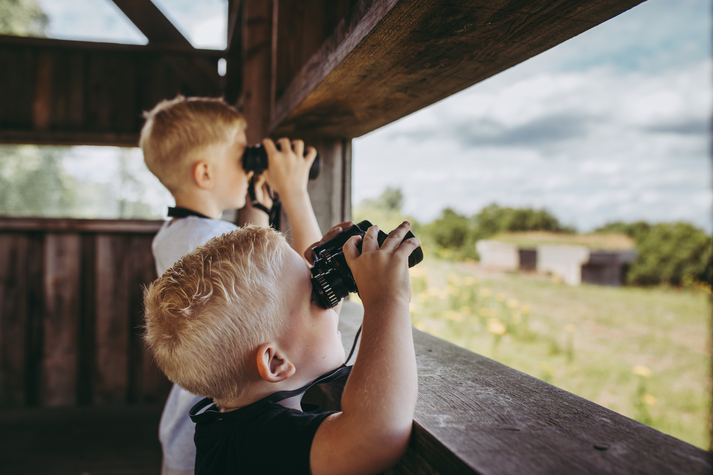 2 kinderen die met een verrekijker aan het kijken zijn