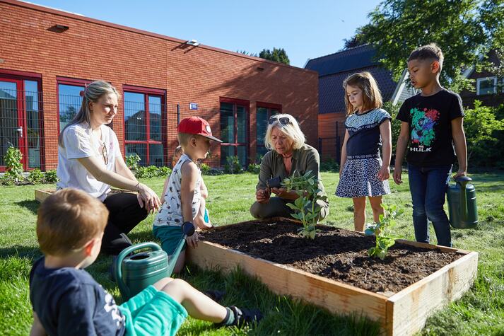 Kinderen met de juf bezig met een moestuinbak